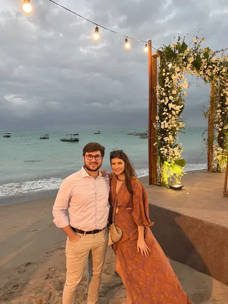 Helena e William à beira-mar, sob um arco iluminado