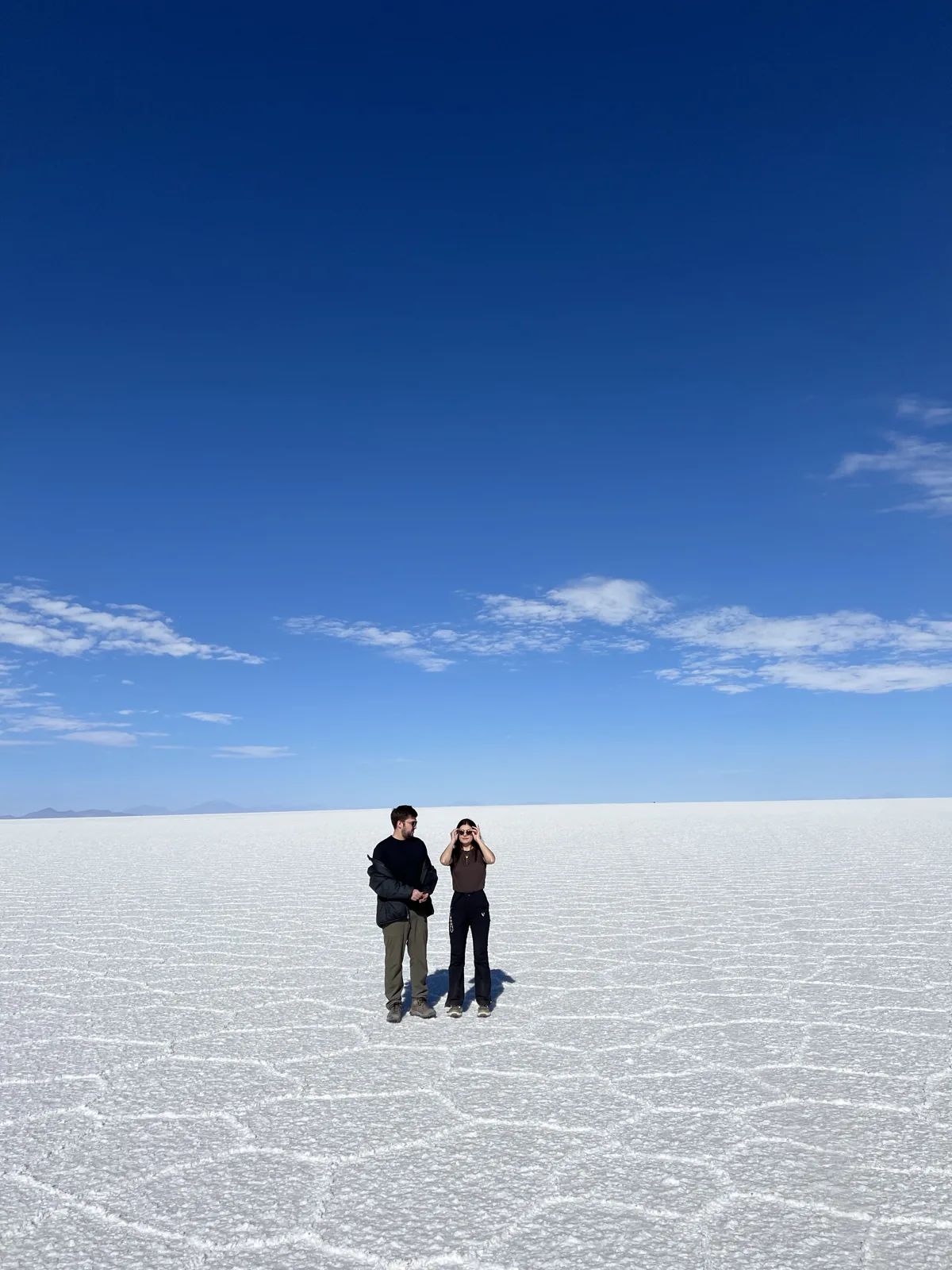 Helena e William juntos na imensidão de um deserto de sal, sob o céu azul