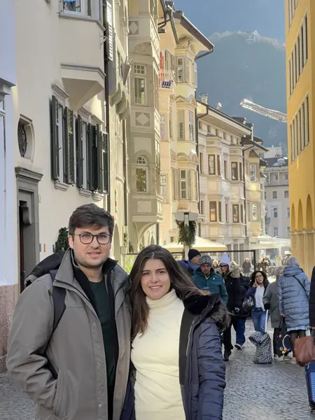 Helena e William em uma rua de fachadas claras